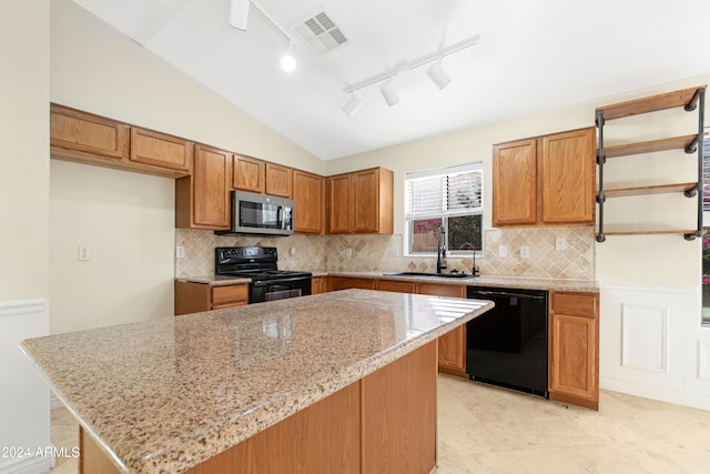 kitchen with sink, light stone counters, a center island, black appliances, and lofted ceiling