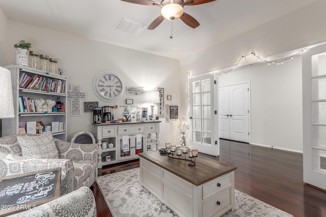 living room with wood finished floors, visible vents, a ceiling fan, and baseboards