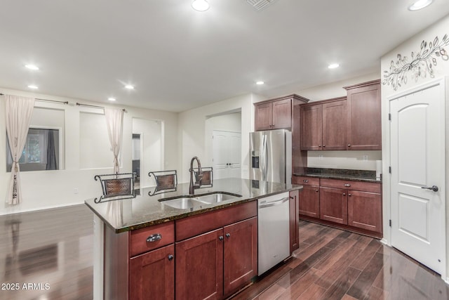 kitchen with recessed lighting, dark stone counters, stainless steel appliances, dark wood-style flooring, and a sink