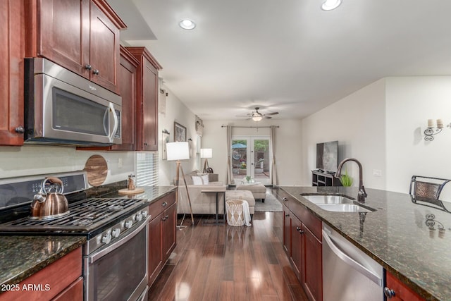 kitchen with a sink, ceiling fan, stainless steel appliances, open floor plan, and dark wood finished floors