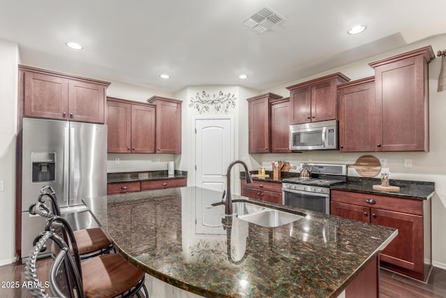 kitchen with a sink, appliances with stainless steel finishes, visible vents, a kitchen bar, and recessed lighting
