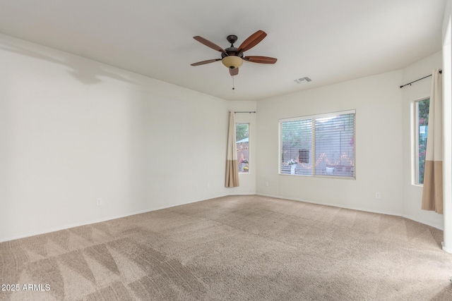 empty room featuring carpet, ceiling fan, visible vents, and baseboards
