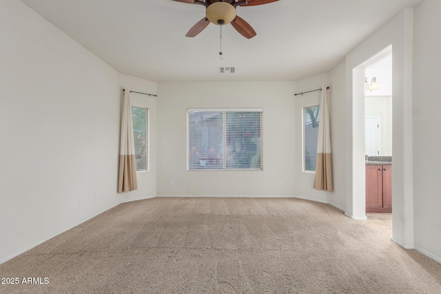 unfurnished room with visible vents, a ceiling fan, and light colored carpet