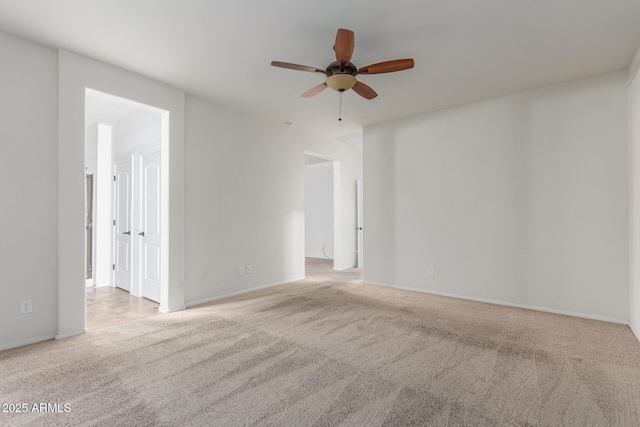 carpeted spare room featuring a ceiling fan and baseboards