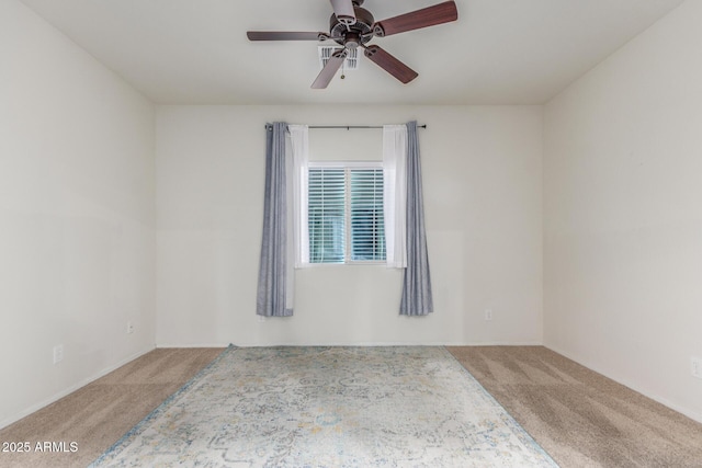 carpeted spare room featuring baseboards and a ceiling fan