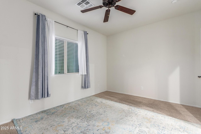 carpeted empty room featuring ceiling fan and visible vents