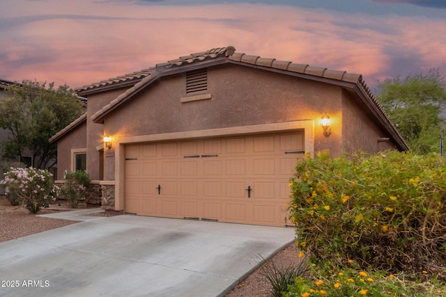 view of front of property featuring driveway, a garage, stucco siding, and a tiled roof