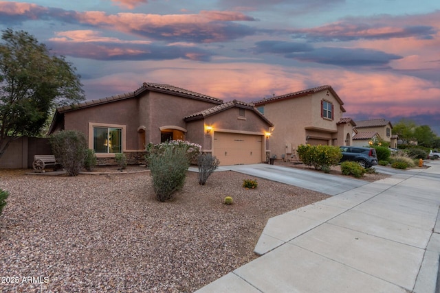 view of front of house with a garage, a tile roof, stucco siding, and driveway