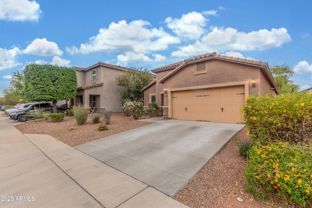 view of front of property featuring stucco siding, a tile roof, concrete driveway, and an attached garage