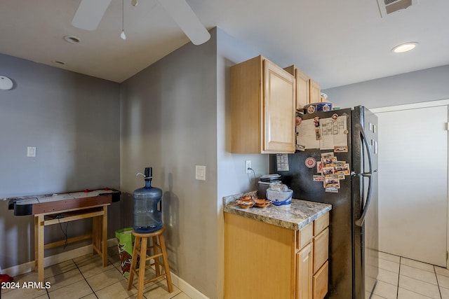 kitchen featuring light brown cabinetry, ceiling fan, black refrigerator, and light tile patterned flooring