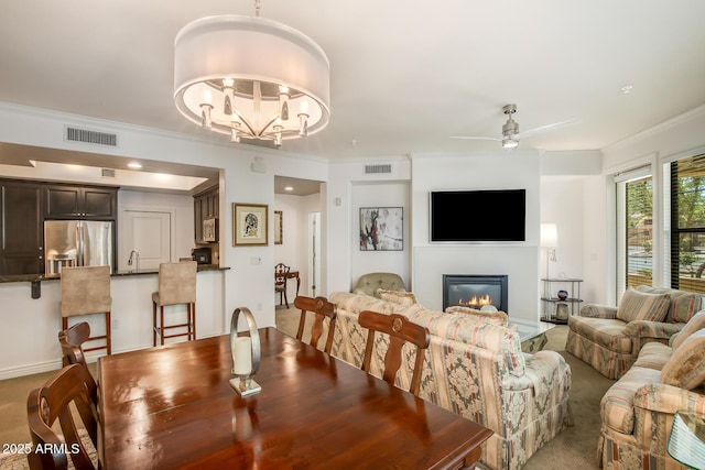 dining room with ornamental molding, a glass covered fireplace, ceiling fan, and a chandelier