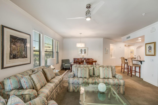 living room featuring carpet, ornamental molding, ceiling fan, and baseboards