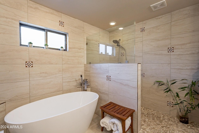 bathroom featuring visible vents, recessed lighting, a freestanding bath, a walk in shower, and tile walls