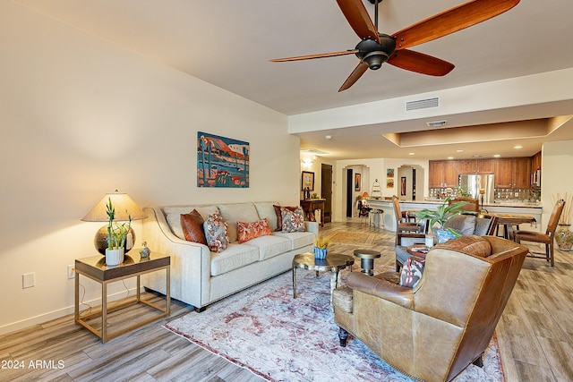 living area featuring visible vents, ceiling fan, light wood-type flooring, and baseboards