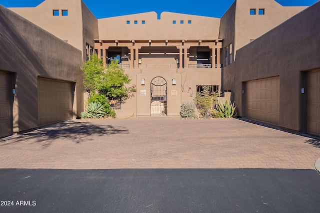 pueblo revival-style home with a gate, driveway, and stucco siding