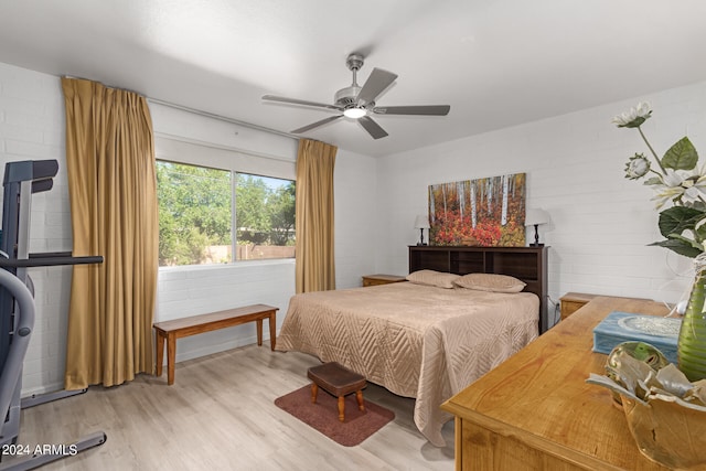 bedroom with brick wall, light hardwood / wood-style floors, and ceiling fan