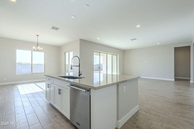 kitchen featuring white cabinetry, sink, stainless steel dishwasher, a notable chandelier, and a kitchen island with sink