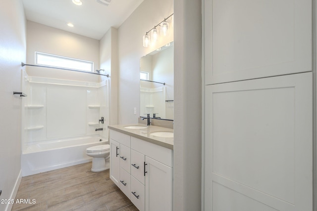 full bathroom with vanity, hardwood / wood-style flooring, washtub / shower combination, and toilet