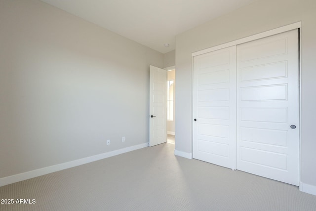 unfurnished bedroom featuring light colored carpet and a closet