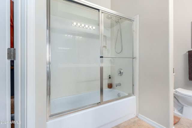 bathroom featuring toilet, tile patterned floors, and shower / bath combination with glass door