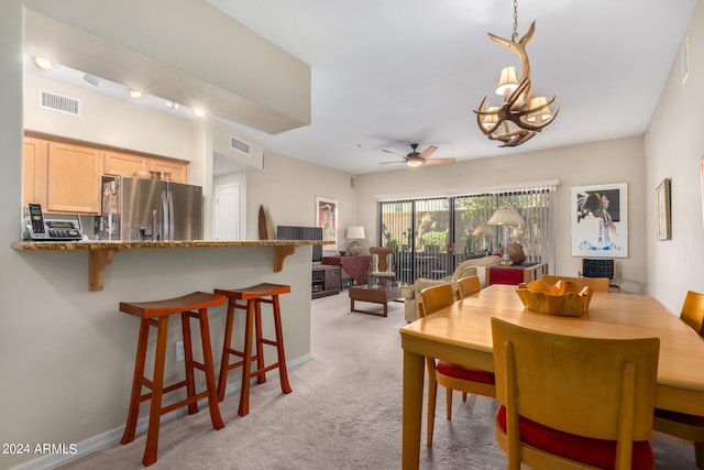 dining area featuring light carpet and ceiling fan with notable chandelier