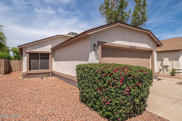 view of home's exterior featuring a garage, stucco siding, and fence