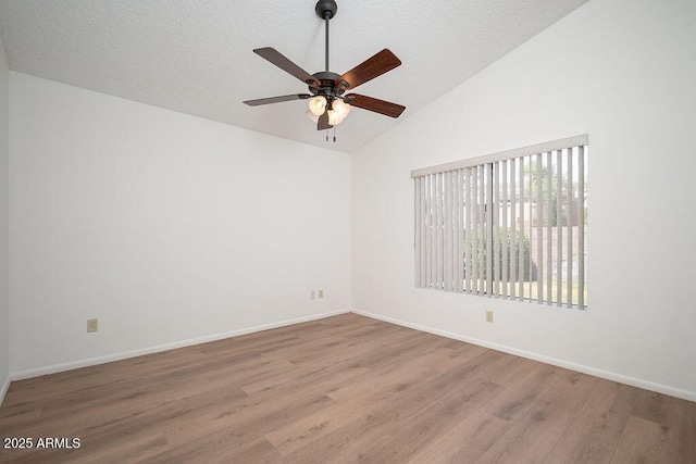 spare room with baseboards, ceiling fan, wood finished floors, and lofted ceiling