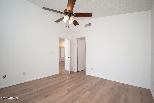 spare room featuring baseboards, ceiling fan, wood finished floors, and visible vents
