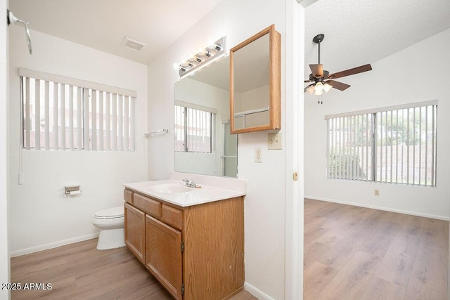 bathroom with ceiling fan, vanity, toilet, wood finished floors, and lofted ceiling