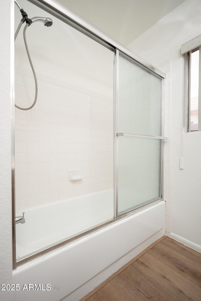 full bath featuring baseboards, combined bath / shower with glass door, and wood finished floors