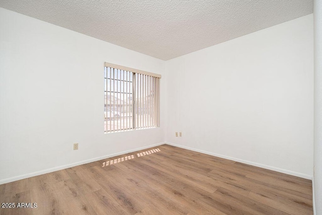 spare room with baseboards, a textured ceiling, and wood finished floors