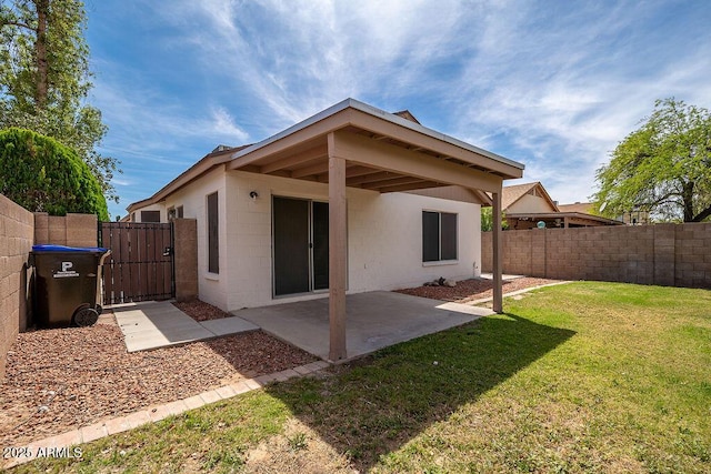 rear view of property with a lawn, a gate, fence private yard, a patio area, and concrete block siding