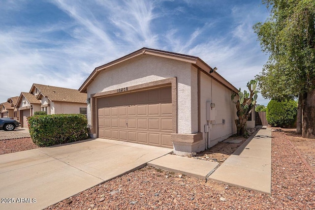 exterior space featuring a garage, fence, stucco siding, and driveway