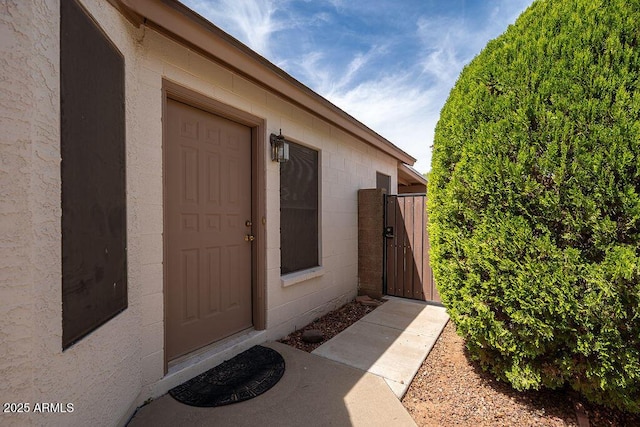 view of exterior entry with concrete block siding and a gate