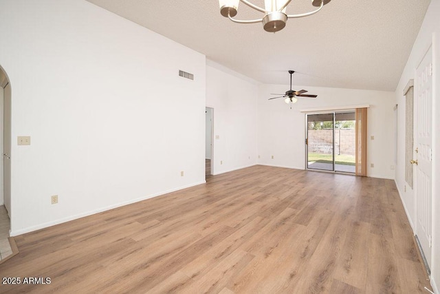 unfurnished room featuring visible vents, arched walkways, light wood-style flooring, ceiling fan with notable chandelier, and vaulted ceiling