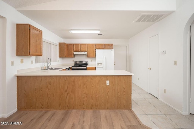 kitchen with a sink, stainless steel electric stove, white fridge with ice dispenser, under cabinet range hood, and visible vents