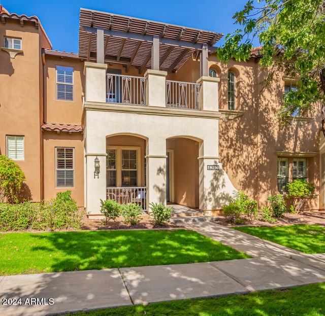 view of front of home with a front yard and a balcony