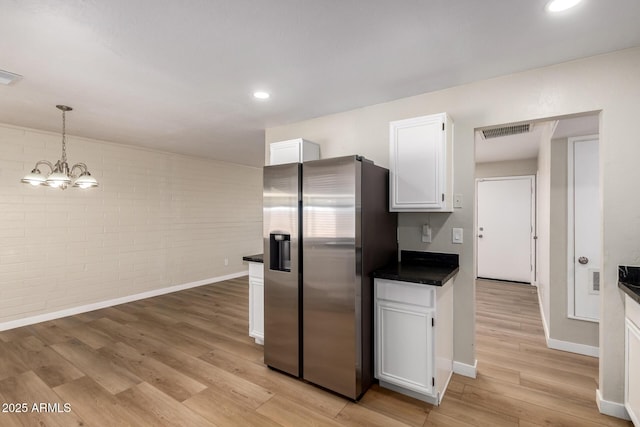 915 E Commonwealth Pl, Chandler, AZ 85225 - kitchen with stainless steel fridge, dark countertops, brick wall, white cabinetry, and light wood-style flooring