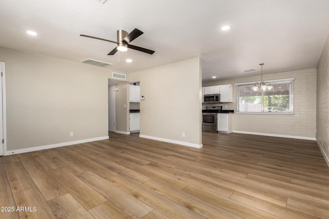 915 E Commonwealth Pl, Chandler, AZ 85225 - unfurnished living room featuring a chandelier, wood finished floors, a ceiling fan, brick wall, and recessed lighting