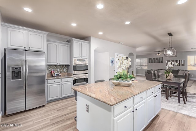 kitchen featuring a kitchen island, white cabinetry, stainless steel appliances, tasteful backsplash, and hanging light fixtures