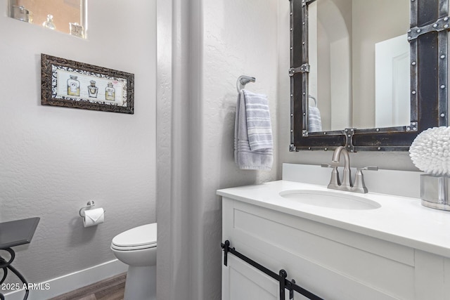 bathroom featuring wood-type flooring, toilet, and vanity