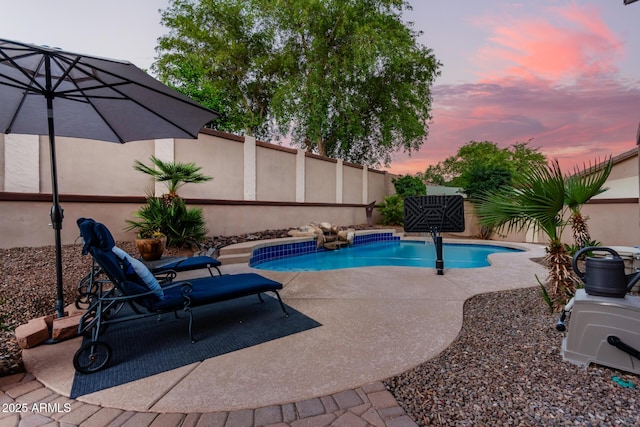 pool at dusk with a patio area