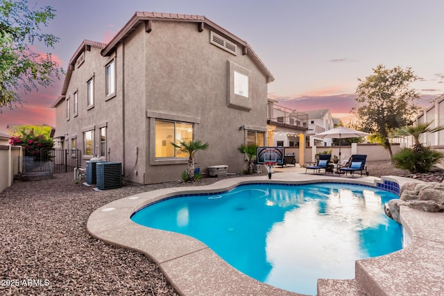 pool at dusk with central air condition unit and a patio