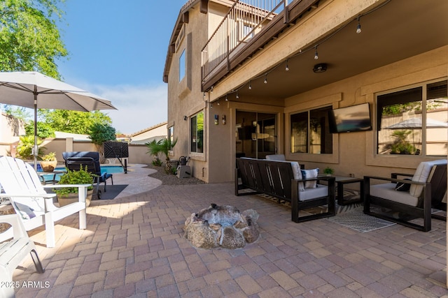 view of patio / terrace with a balcony and an outdoor living space with a fire pit