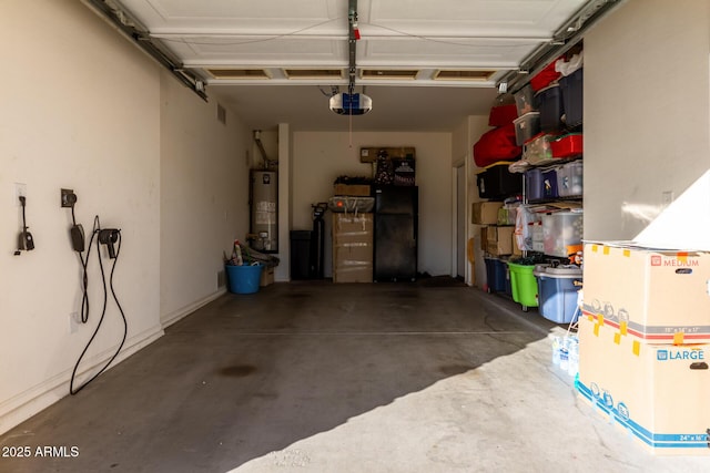 garage featuring gas water heater, black fridge, and a garage door opener