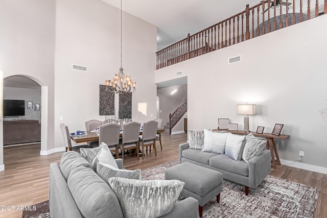 living room featuring a notable chandelier, hardwood / wood-style flooring, and a high ceiling