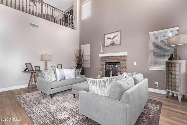 living room featuring a fireplace, wood-type flooring, and a high ceiling