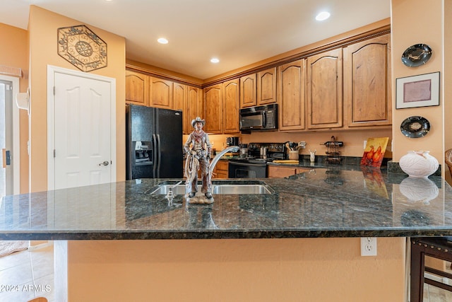 kitchen with black appliances, kitchen peninsula, sink, dark stone countertops, and light tile patterned flooring