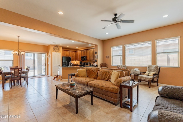 tiled living room with ceiling fan with notable chandelier