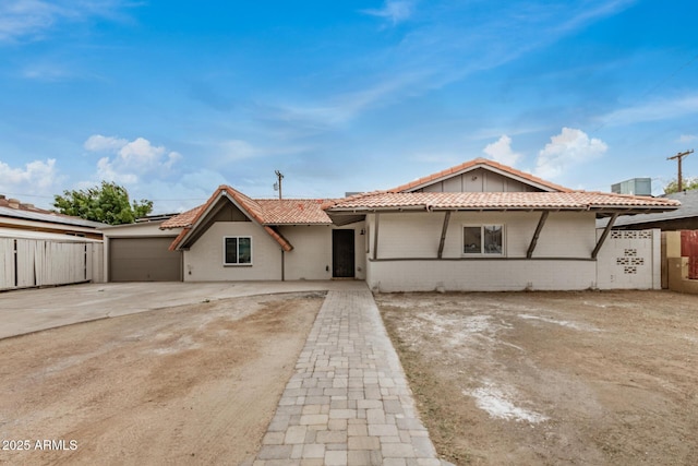 view of front facade featuring fence, driveway, a garage, a tile roof, and brick siding